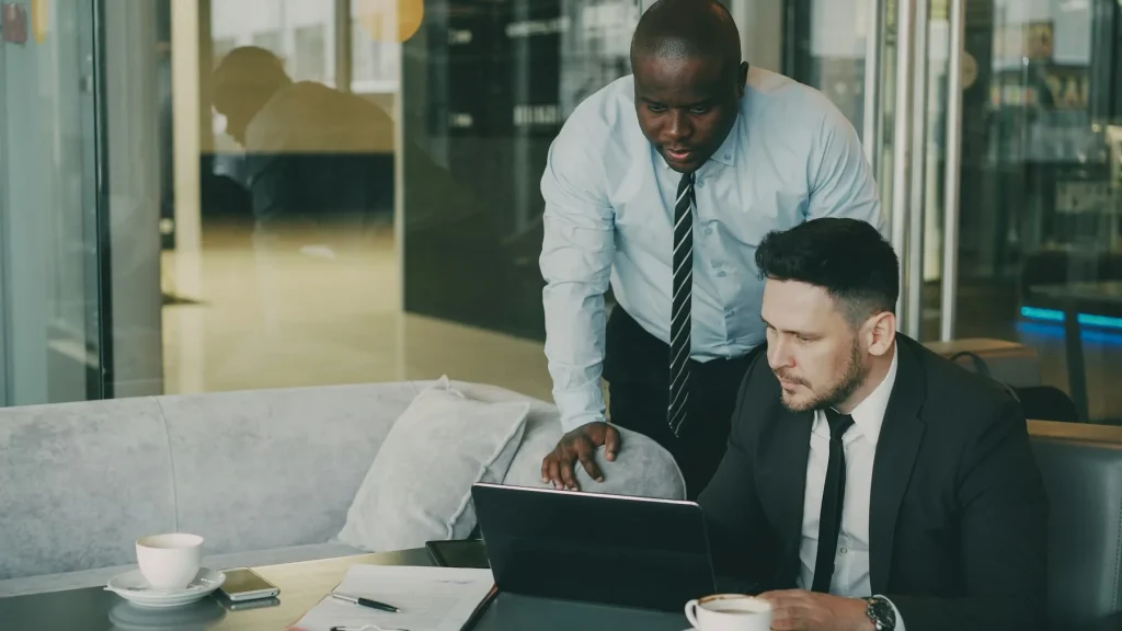 Two people discussing a project beside a laptop